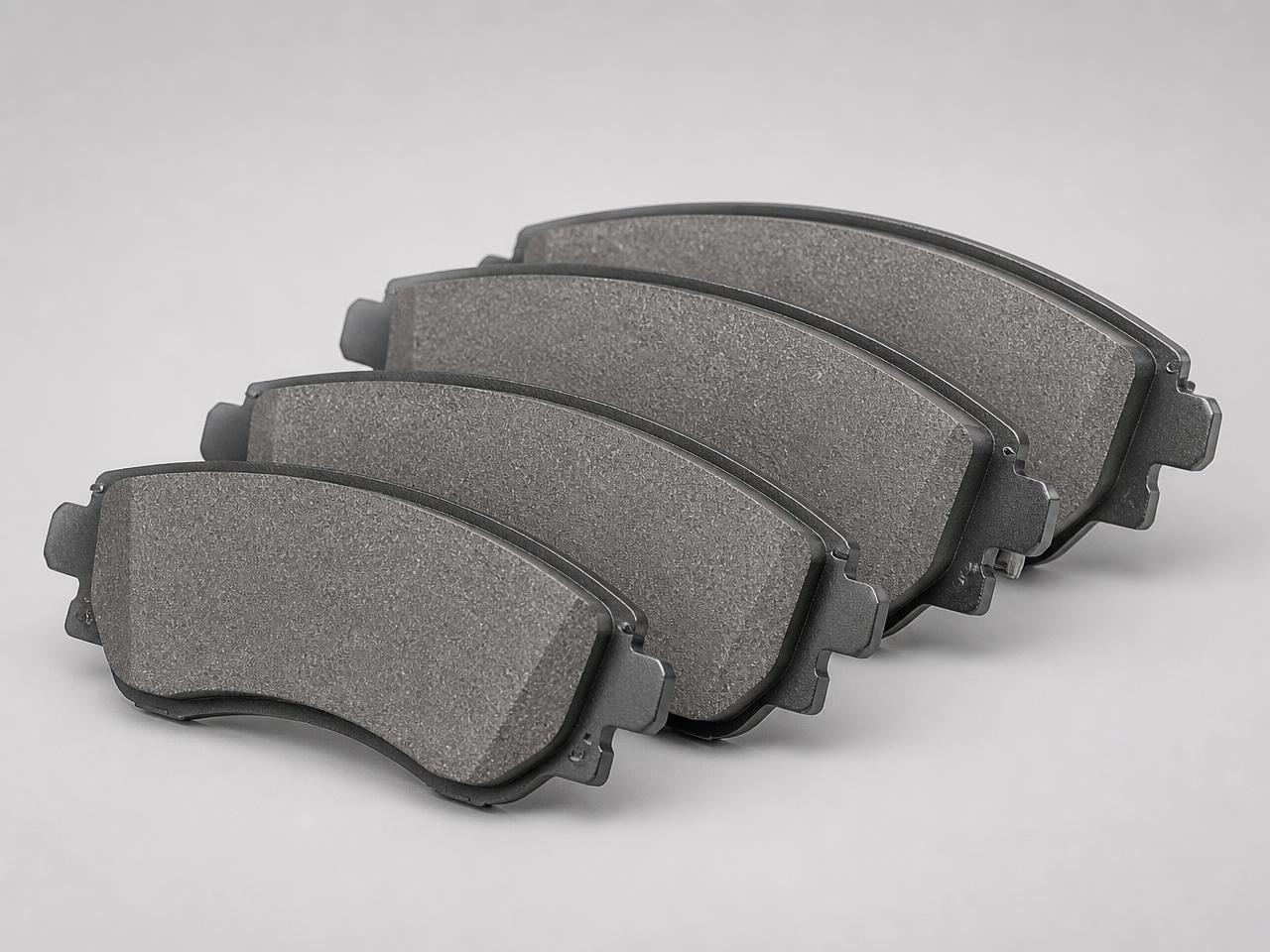 Set of four automotive brake pads with friction material