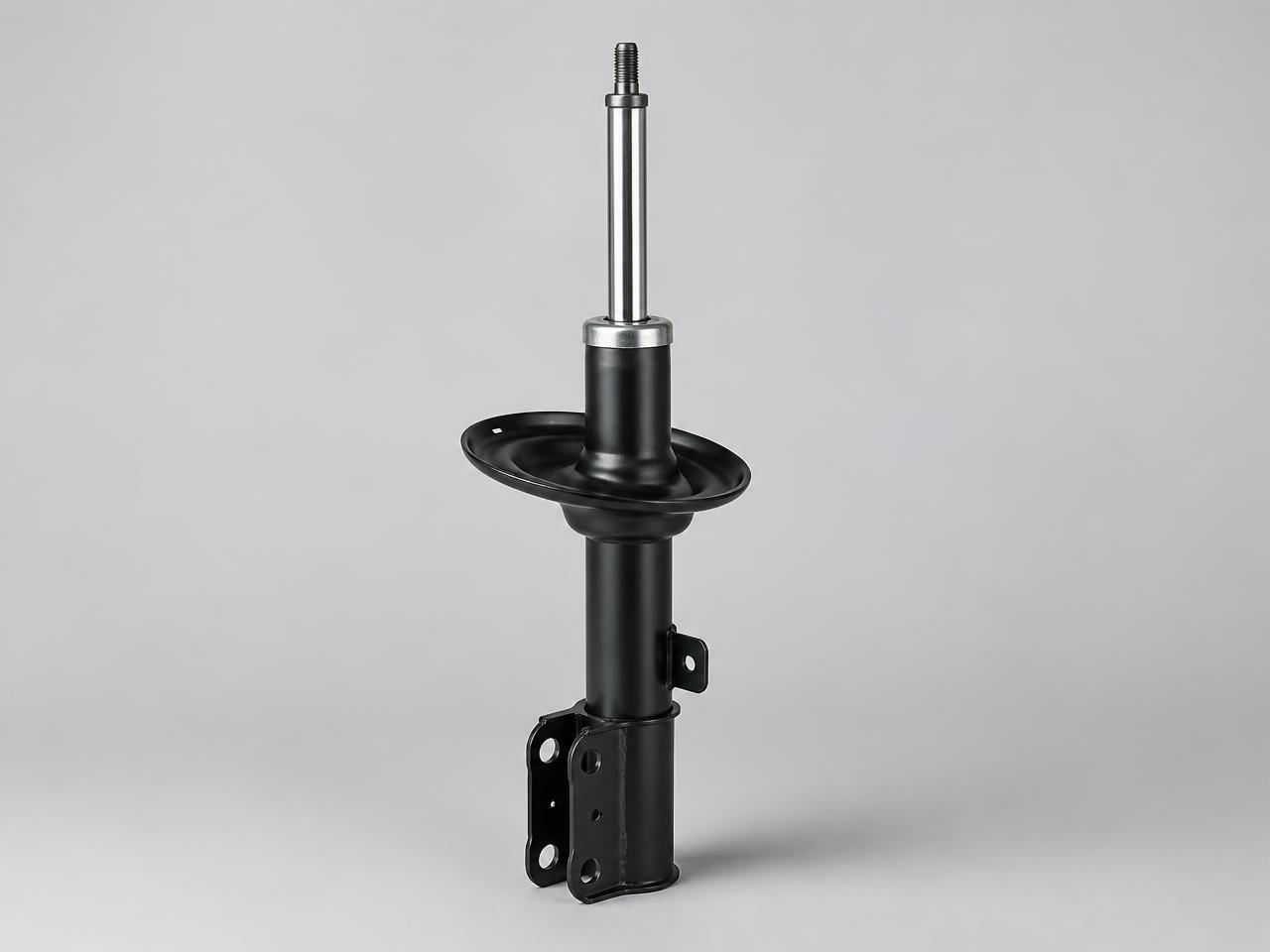 Black automotive shock absorber strut on a light studio background